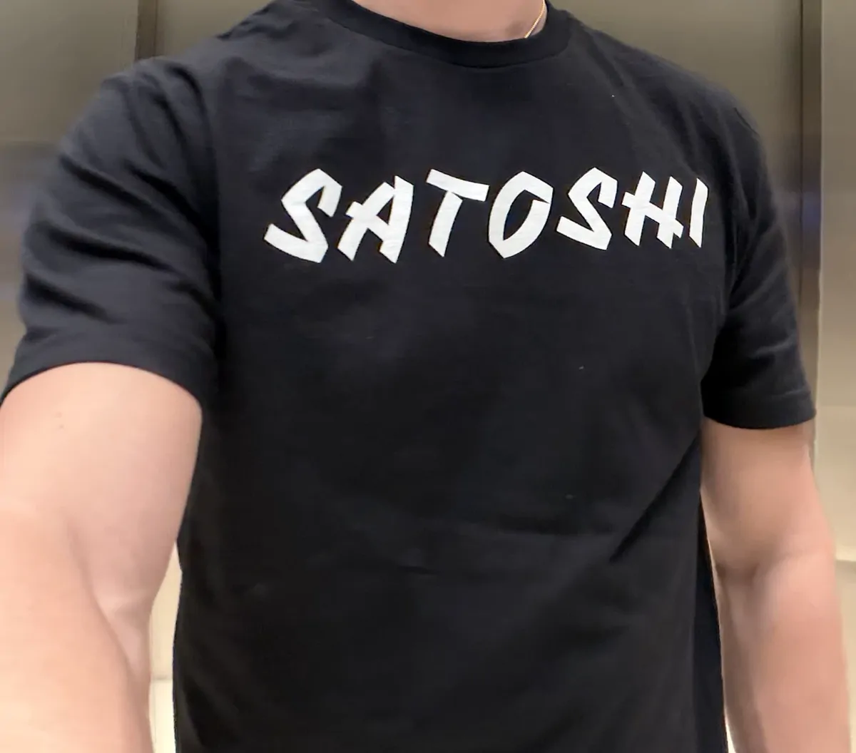 La playera negra con SATOSHI en letra de pincel blanca, puesta